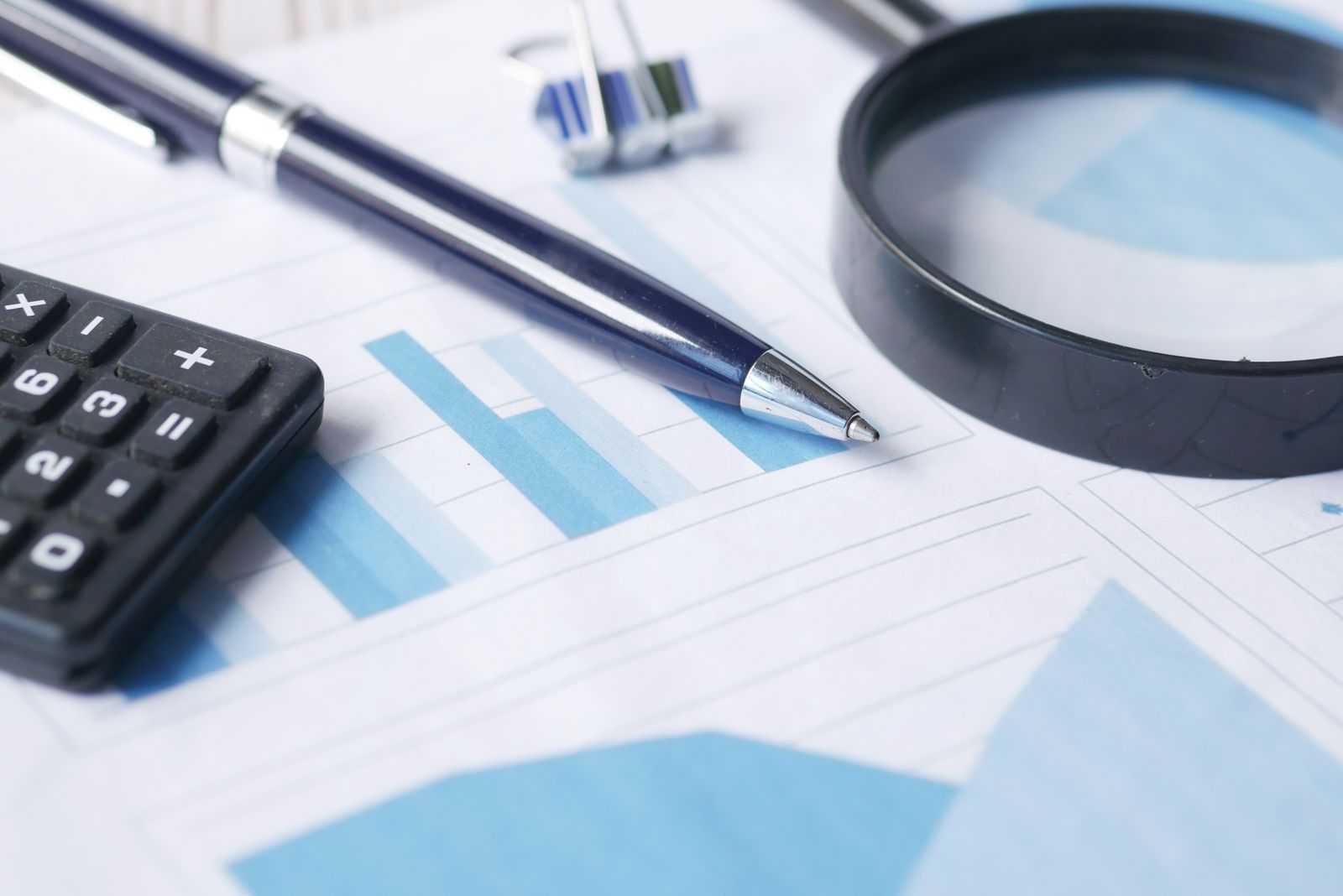 Pen, calculator, and magnifying glass on a financial chart